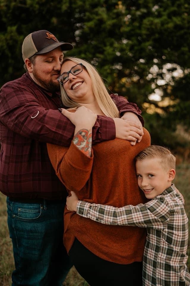 Brock Hood-Wright outdoors with his wife and son